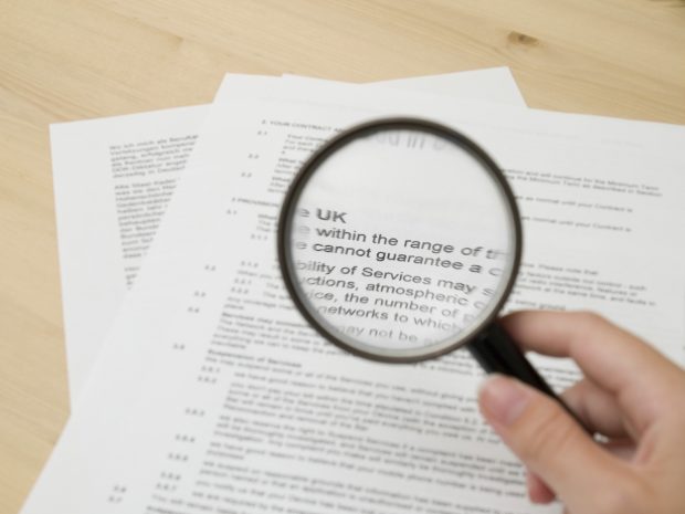 Image of of a page of text with a magnified glass being held up in front of it